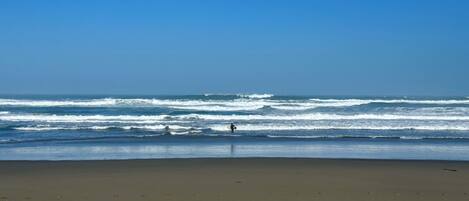 A beach with waves and a person in the water.