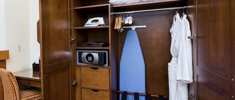 Ein kleines Zimmer mit einem hölzernen Kleiderschrank, einem Bügelbrett und einem blauen Bügelbrett.