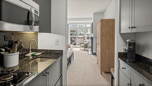 A modern kitchen with a granite countertop, stainless steel appliances, and a view to a balcony. - #374 | Studio | Remodeled Studio | 3rd Floor Mt Mansfield Views (Stowe)