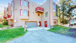 Ein zweistöckiges Wohnhaus mit Garage, roter Tür und Balkon.