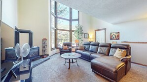 Ein Wohnzimmer mit Kamin, Ledersofa und großem Fenster.