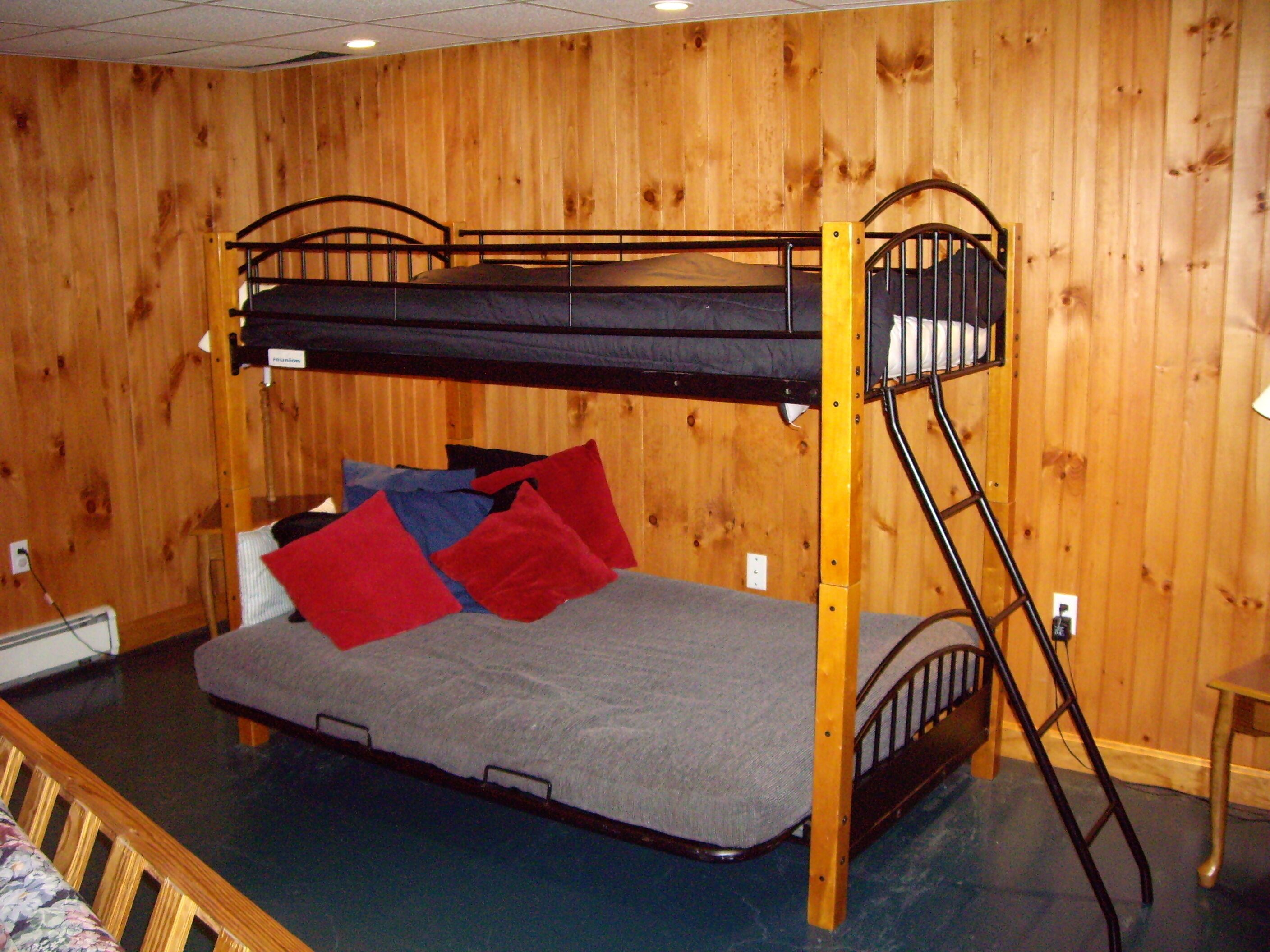 A bunk bed room with a wooden wall, a small table, and a chair.