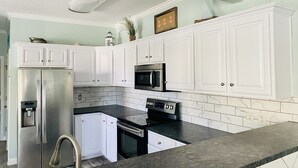 A kitchen with white cabinets, a stainless steel refrigerator, a black oven, and a microwave.
