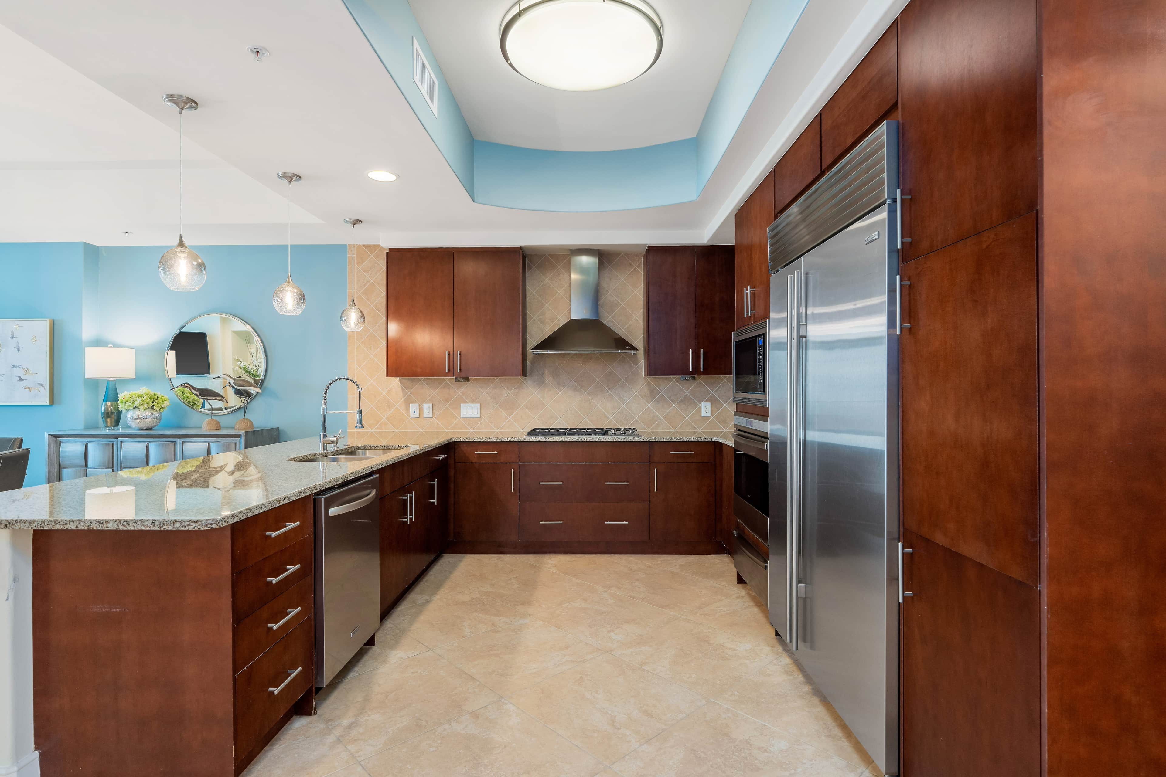 A modern kitchen with dark wood cabinets, stainless steel appliances, and a blue accent wall.