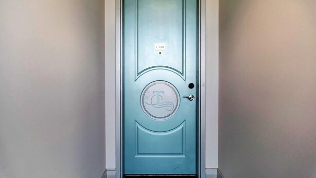 A teal door with a circular emblem and a small plaque above it.