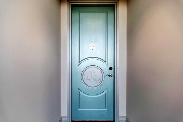 Una puerta azul verdosa con un emblema circular y una pequeña placa encima.