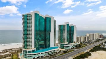 A high-rise hotel with a curved facade, multiple balconies, and a beach view.