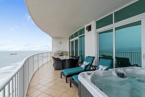 Un balcón con jacuzzi, zona de estar y vista al mar.