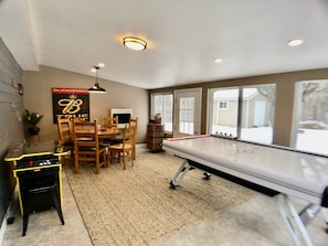 A room with a ping pong table, wooden chairs, a small table with electronic equipment, and a poster on the wall.