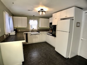 A modern kitchen with white cabinets, a black countertop, and a built-in oven.
