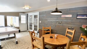 A dining area with a round wooden table, wooden chairs, and a pool table. There is a sign on the wall that reads "Dodge Hwy." - Amazing Updated Retreat with Fully Stocked All Seasons Game Room!  (St. Helen)