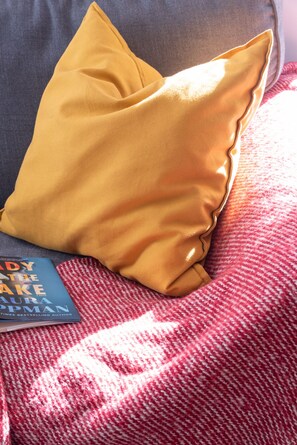 A bed with a red and white patterned blanket, a yellow pillow, and a book titled "The Lady on the Lake" by Laura Robson.