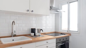 Een moderne keuken met witte kasten, een roestvrijstalen spoelbak, een dubbele oven en een raam voor natuurlijk licht.