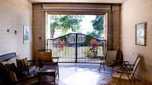 A room with a large sliding door leading to an outdoor area, furnished with a sofa, chairs, and a table.