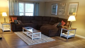 A living room with a sectional sofa, two side tables with lamps, a glass coffee table, and a rug.
