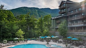 Relax by the resort's large pool surrounded by lounge chairs and umbrellas, with breathtaking views of the lush hills.