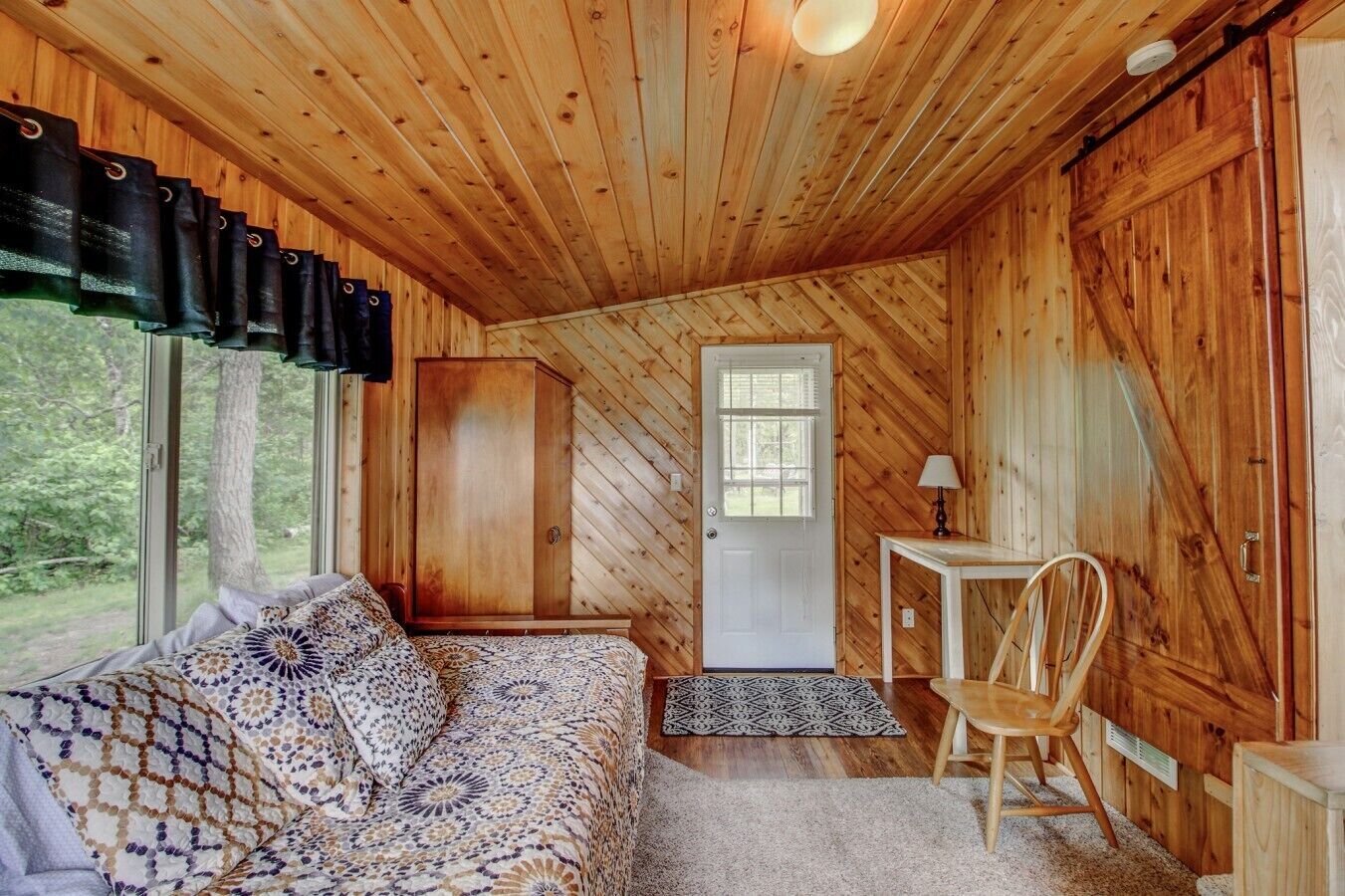 A cozy cabin interior with a bed, a desk, and a chair.