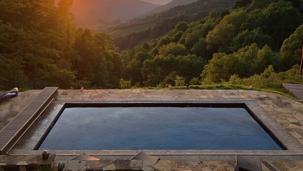 A stone pool with a view of a sunset over a forested valley. - Incredible Mtn Views - 106 Acres: Private Pool, Pickleball Fall of 2026 (Zionville)