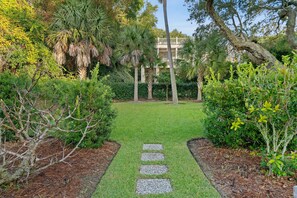 A garden pathway leading to a building with a balcony.