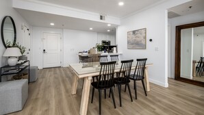 Eine moderne Küche mit weißen Schränken, einem Esstisch mit schwarzen Stühlen und einem großen Spiegel an der Wand.