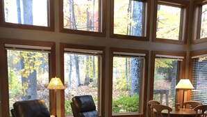 Un salon spacieux doté de grandes fenêtres, de meubles en bois et d’une cheminée.
