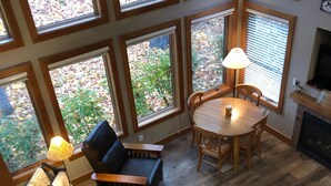 Un vaste espace de vie doté d’un haut plafond, de grandes fenêtres, d’une table ronde en bois, d’un canapé et d’une cheminée.