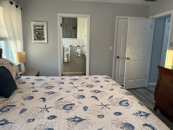 A bedroom with a bed, a nightstand, a dresser, a door, and a framed picture on the wall. - Canal side location with beach & pool club membership! (Key Colony Beach)