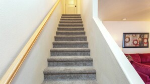 A carpeted staircase with a wooden handrail leading to a door. - Kanab Retreat Near Zion w/ Pool & Hot Tub (Kanab)