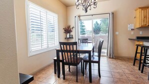 A dining area with a table and chairs, a chandelier, and a view through a glass door to an outdoor patio. - Kanab Retreat Near Zion w/ Pool & Hot Tub (Kanab)