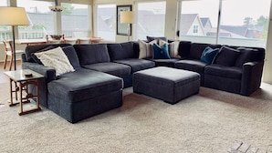 A modern living room with a sectional sofa, ottomans, and a dining area with a table and chairs. - Beautiful Manzanita Getaway- Perfect for Family Large or Small - MCA #769 (Manzanita)