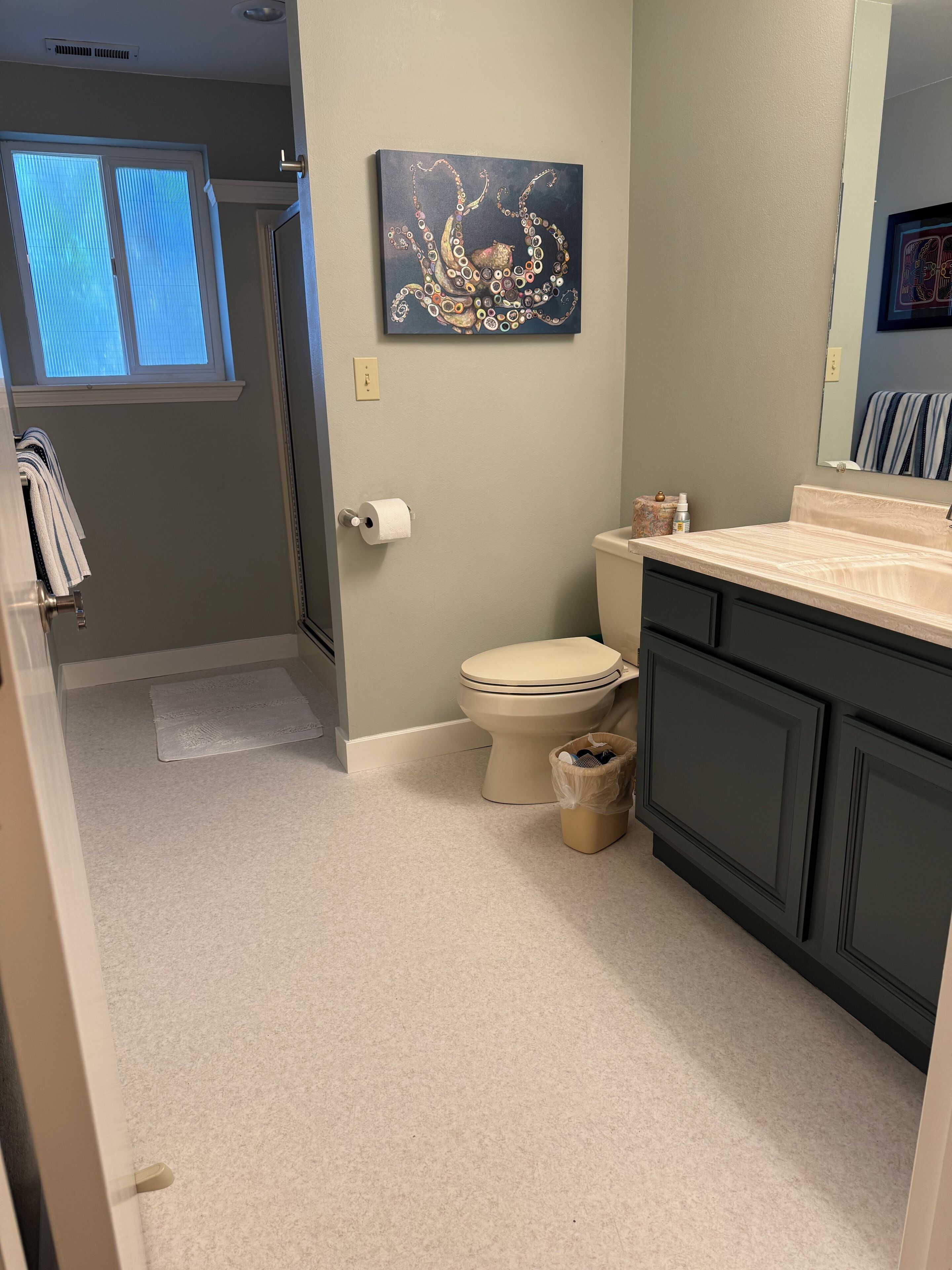 A bathroom with a toilet, sink, and a painting on the wall.
