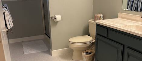 A bathroom with a toilet, sink, and a painting on the wall.