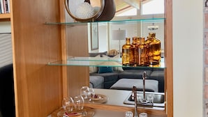 A compact kitchenette with a glass shelf holding kitchenware, a sink, and a mirror reflecting the room. - Beautiful Manzanita Getaway- Perfect for Family Large or Small - MCA #769 (Manzanita)