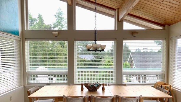 A spacious dining area with a large wooden table and six chairs, large windows with blinds, and a hanging light fixture. - Beautiful Manzanita Getaway- Perfect for Family Large or Small - MCA #769 (Manzanita)