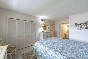 Een slaapkamer met een bed, een kaptafel, een stoel, een kast en een badkamer die door een open deur zichtbaar is.