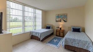 A bedroom with two beds, a painting on the wall, and a window with blinds. - INCREDIBLE view of Palm Aire CC golf course from first floor Condo! (Sarasota)