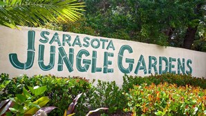 A sign for Sarasota Jungle Gardens with lush greenery and tropical plants. - INCREDIBLE view of Palm Aire CC golf course from first floor Condo! (Sarasota)