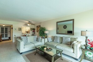 A living room with two sofas, a coffee table, a large mirror, and a ceiling fan.