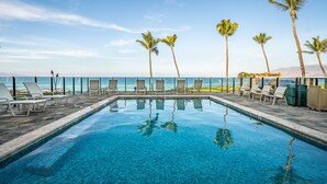 A swimming pool with lounge chairs and palm trees, overlooking a beach and ocean. - 104 - Lovely Ground Floor Direct Oceanfront + Larger Lanai (Kihei)