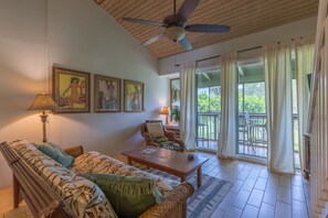 A living room with a sofa, armchair, and coffee table. There are ceiling fans, a lamp, and a window with curtains. - Awesome North Shore Getaway Turtle Bay w/ pool, family safe beach, tennis, golf (Kahuku)