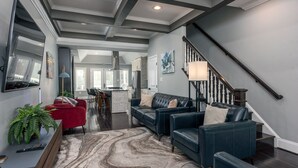 A modern living room with dark leather sofas, a marble-patterned rug, and a large flat-screen TV mounted on the wall. -  Luxe Three floors. Four bedrooms each with private full bath  Garage Parking (Washington)