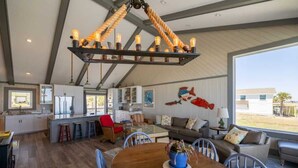Una cocina amplia con una isla central, un comedor con mesa de madera y una sala de estar con sofá y sillones.