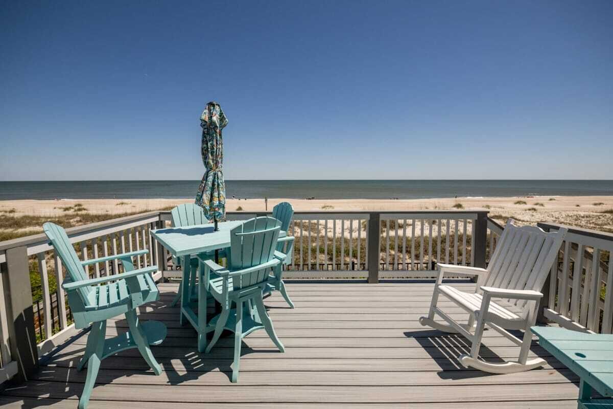 Een terras met tafel en stoelen met uitzicht op het strand.