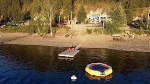 Une propriété au bord du lac, dotée d’un quai, d’une plateforme flottante et d’une maison en arrière-plan.