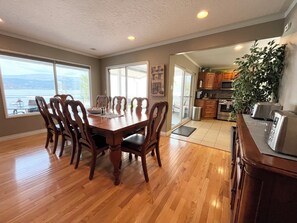 A dining area with a wooden table and chairs, a kitchen with modern appliances, and a view of the outdoors.