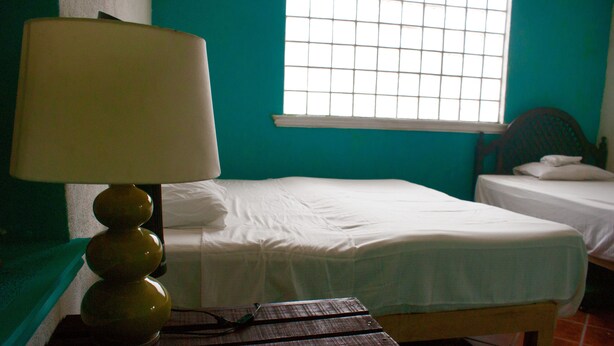 Una habitación con dos camas, una ventana de diseño cuadriculado y una lámpara sobre una mesa.