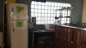 Una cocina con refrigerador, una ventana con persianas, un fregadero y una encimera con varios objetos.