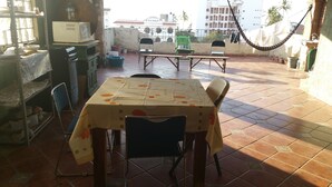 Un comedor con una mesa cubierta por un mantel, sillas y vista a un edificio residencial al fondo.