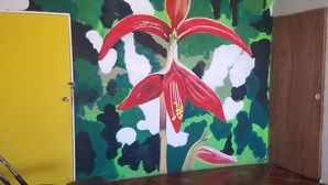 Una habitación con un gran mural floral en la pared, una puerta amarilla y equipo de ejercicio.