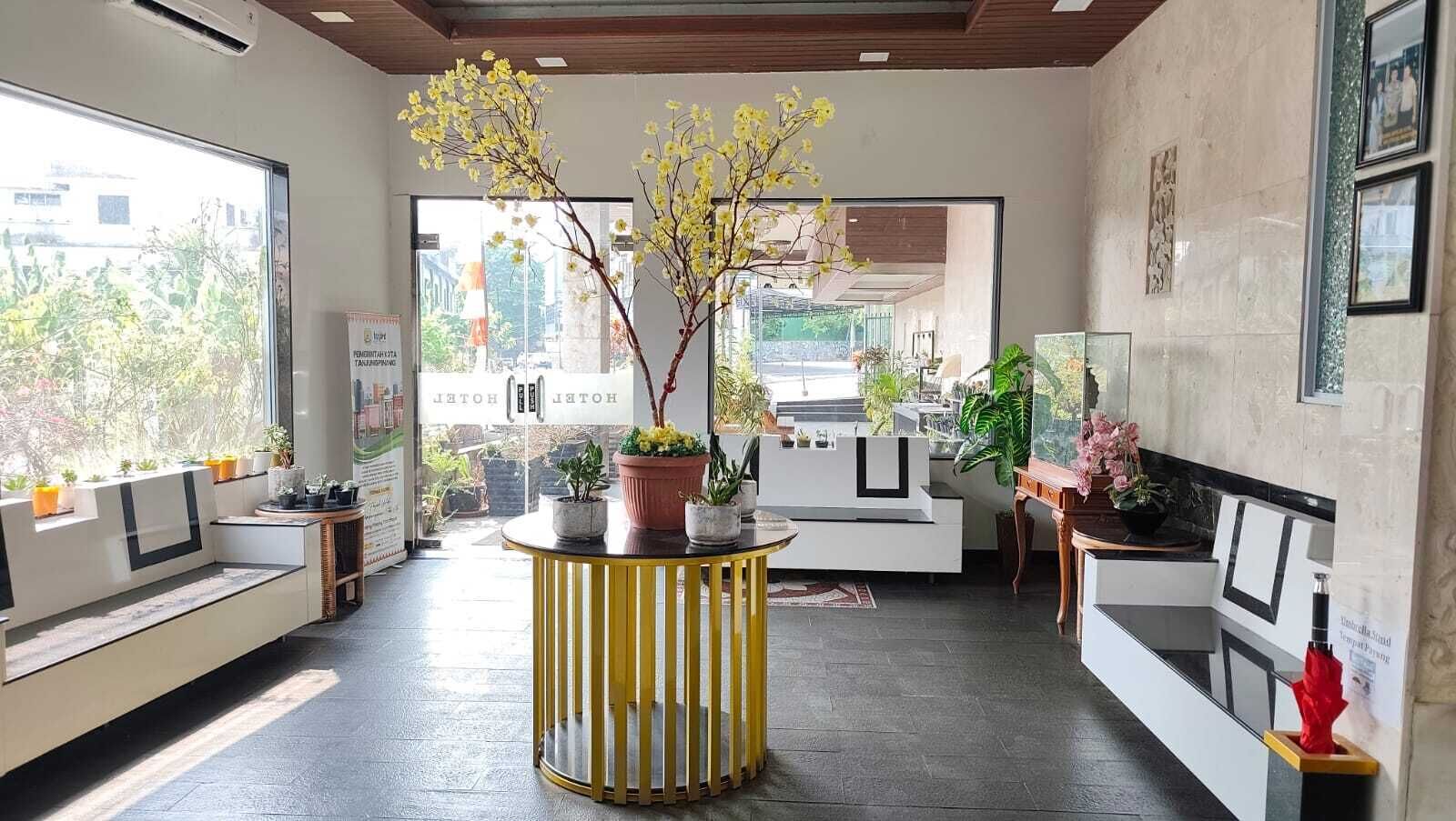 A hotel lobby with a central round table, seating area, and a view of the outside.